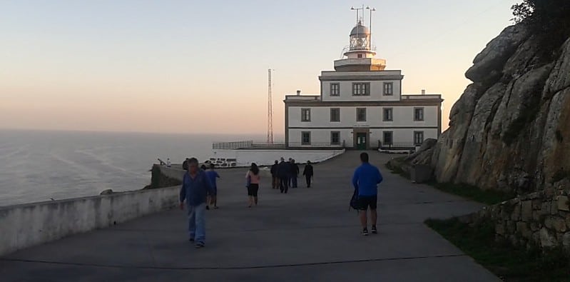 a picture of a group of pilgrims walking to the lighthouse on the Camino