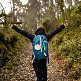 happy pilgrim young woman on the train path road walking backpack